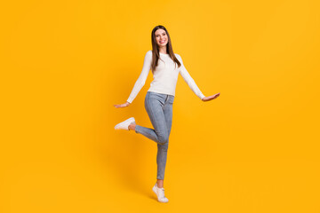 Fototapeta na wymiar Full size photo of optimistic brunette girl stand wear white sweater jeans sneakers isolated on yellow color background