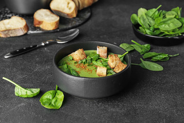 Bowl with tasty spinach soup on dark background