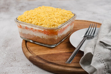 Traditional russian salad Mimosa with vegetables and fish. Layered salad with potatoes, tuna, carrot, onion, eggs and mayonnaise.