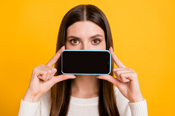 Photo of optimistic brunette girl show telephone wear white sweater isolated on yellow color background