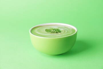 Bowl with tasty spinach soup on color background