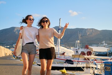 Sea family vacation together, happy mom and teenage daughter walking along the pier