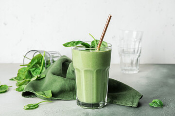 Glass of healthy spinach smoothie on color background