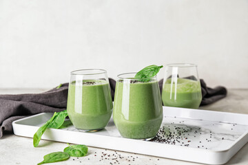 Glasses of healthy spinach smoothie on light table