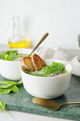 Bowls with tasty spinach soup on table