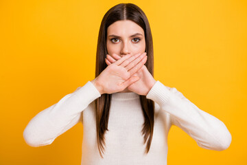 Portrait of young person arms palms crossed covering mouth do not speaking isolated on yellow color...