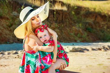 Mom and daughter on the seashore in summer in dresses