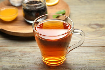 Glass cup of hot black tea on wooden table