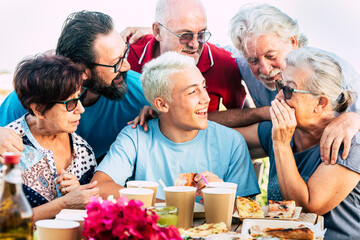 Group of mixed generations ages of people have fun together during pizza lunch - teenager adult and senior men and women smile and laugh celebrating outdoor - cheerful beautiful family friends