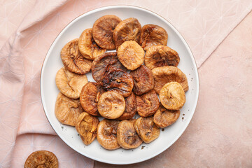 Plate with tasty dried figs on color background