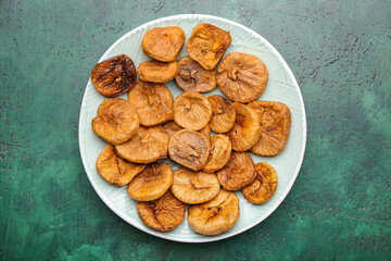 Plate with tasty dried figs on color background