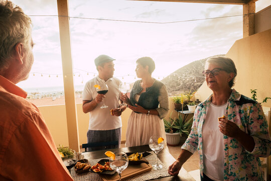 Group of mixed ages people enjoy food and drinks together in friendship - family elebration in the terrace at home - people have fun together