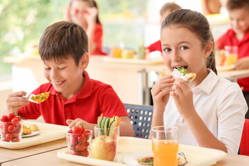 Pupils having healthy lunch in classroom