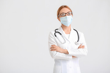 Portrait of female doctor wearing medical mask on light background