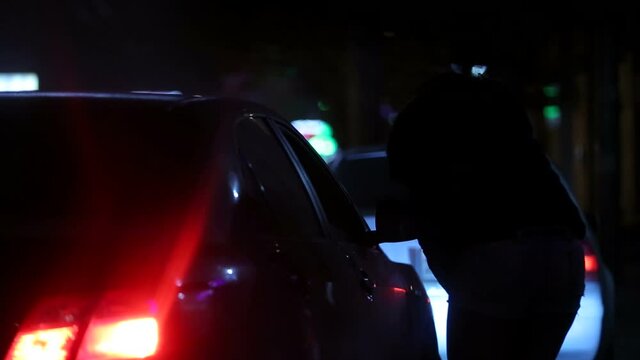 Woman prostitute approaches the client's car. Woman talking to client through car window