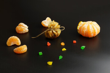 One thin ruddy pancake with filling, wrapped in a bag and tied with thread, next to candied fruits and tangerines.