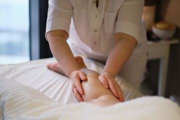 Obraz na płótnie Canvas Detail of hands massaging human calf muscle.Therapist applying pressure on female leg. Hands of massage therapist massaging legs of young woman in spa salon. Body care in spa salon for young woman.