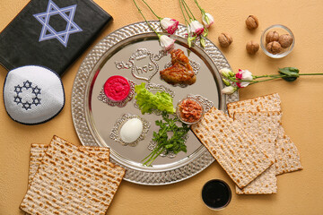Passover Seder plate with traditional food, Torah and Jewish cap on color background