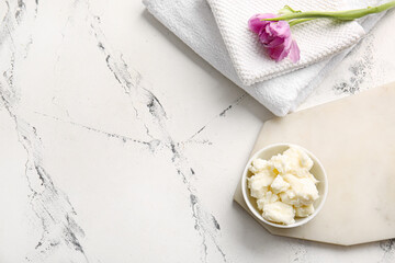 Bowl with shea butter and towels on white background