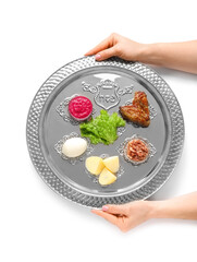 Female hands with Passover Seder plate and traditional food on white background