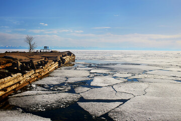 Lake Baikal in the spring. Time to release the frozen lake from the ice. Old wooden pier. Ice floes and open water. 