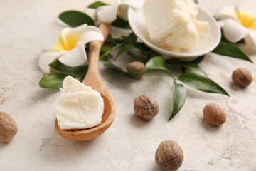 Spoon with shea butter on light background