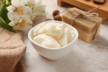 Bowl with shea butter on light background