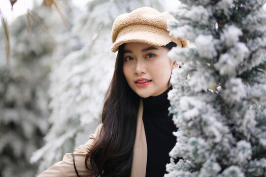 Portrait of young beautiful woman in winter clothes. while posing on snow background. Outdoor close-up photo of female model with romantic smile chilling in park in winter.