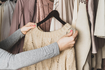 Woman choosing woolen sweater in home cupboard. Season concept