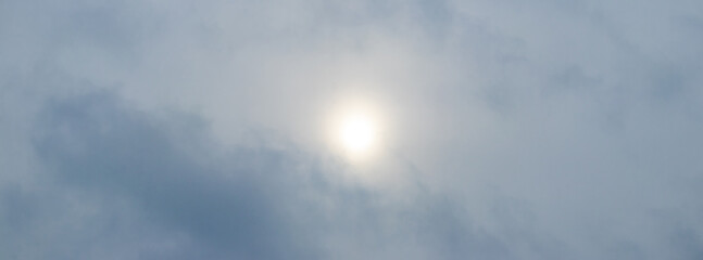 The dim sun peeks through the clouds, the cloudy sky, the panorama