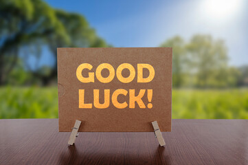 Good luck text on card on the table with sunny green park background.