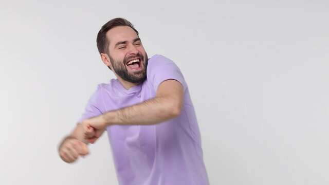 Cheerful funny bearded young man 20s years old in casual violet t-shirt isolated on white background studio. People lifestyle concept. Dancing clenching fists waving hands pointing snapping fingers