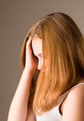 Obraz premium A young European girl holds her head in her hand. The Concept Of Depression, Hopelessness, Sadness, Problems