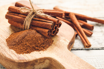 Cinnamon sticks and powder on wooden background