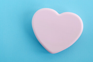 Heart shaped pink bar of soap on a light blue background. Top view, copy space.