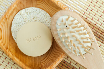 Bar of soap (solid shampoo) and wooden massage hair brush. Eco friendly toiletries. Natural beauty treatment, skin-care or zero waste concept. Top view, copy space.