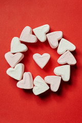 Obraz premium on a red background, a circle of white marshmallows and one heart in the center