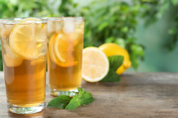 Delicious iced tea on wooden table outdoors, space for text