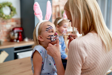 Mother painting Easter bunny on her daughter's face