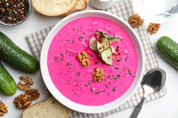 Delicious cold summer beet soup on white wooden table, flat lay