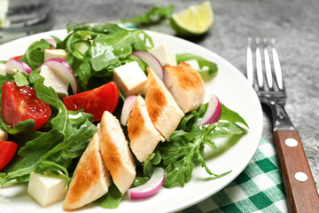 Delicious salad with meat, arugula and vegetables on grey table, closeup