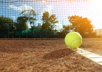 Bright yellow tennis ball on clay court. Space for text
