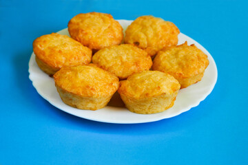 seven cheese muffins made of cottage cheese, eggs and rice flour on a white round plate on a blue background side view. gluten-free food prepared at home. bakery products