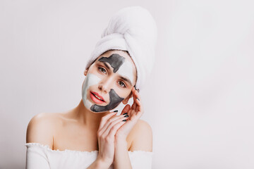 Close-up portrait of attractive girl doing facial mask before bedtime. Adult woman posing on white background