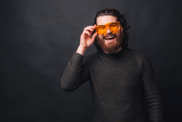 Photo of cheerful bearded man wearing big yellow glasses.