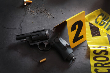Composition with gun and shell casing on black slate table. Crime scene - obrazy, fototapety, plakaty