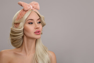 Beautiful blonde woman with a bow on her head on a gray background. Copycpase