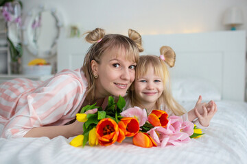 Obraz na płótnie Canvas mom and daughter have breakfast in bed in pajamas