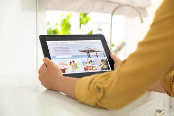 Young woman using tablet to plan trip indoors, closeup. Travel agency concept