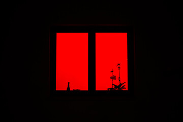 red light from the window. the red window shines mystically at night. mysterious red window
